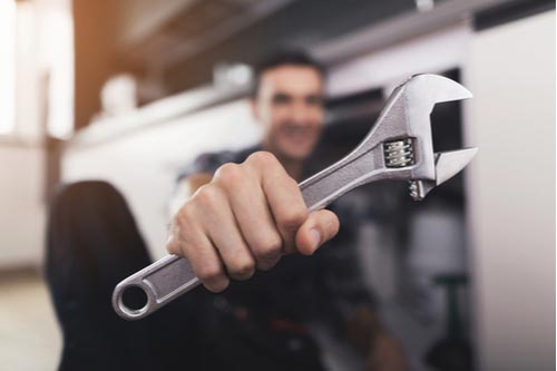 plumber with a wrench working on Miami residential plumbing